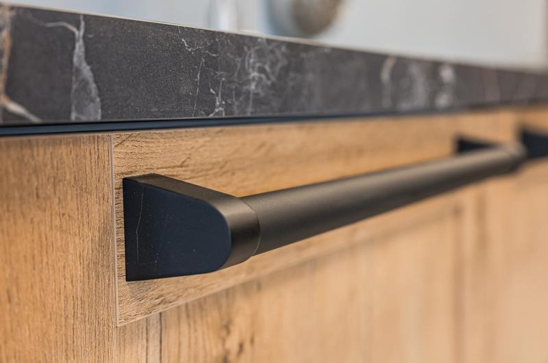 Zwarte handgreep op houten kast met marmeren werkblad